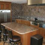 This cherry kitchen is finished with our light honey maple stain.  It features raised panel doors, fluted columns, granite countertops, a large island, stainless steel appliances, an imported pizza oven from Italy, and matching metal countertop height stools.
