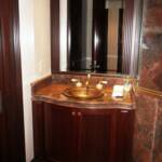 This Cherry wood bathroom vanity features curved doors, a 2 1/2" thick granite countertop with a double bull nose edge, granite backsplash, and a large mirror surrounded by hand carved fluted columns and moldings.  