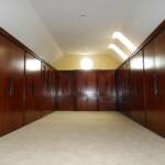 This oversized walk-in, cherry custom closet features large cabinets with 6â€™ foot flat panel doors, full extension drawers, along with glass doors.  It is finished with our Japanese Sienna stain.  
